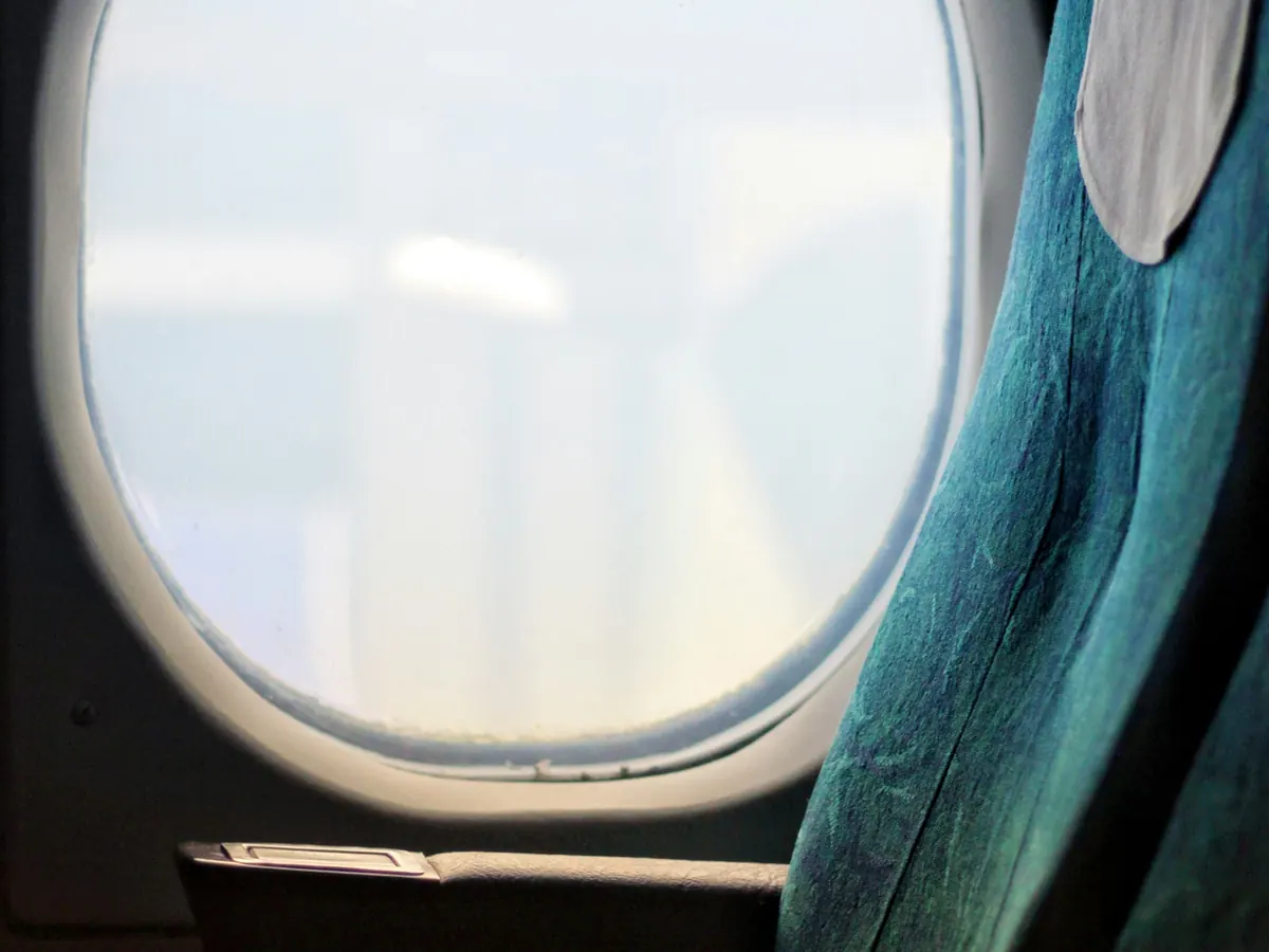 Oval cabin window beside a teal leather seat